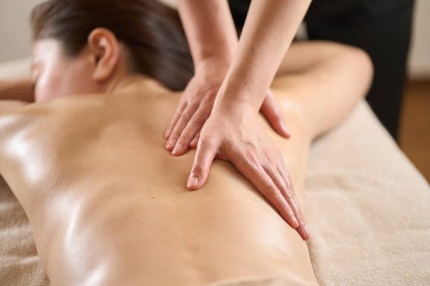 Therapist giving back massage to a woman at spa