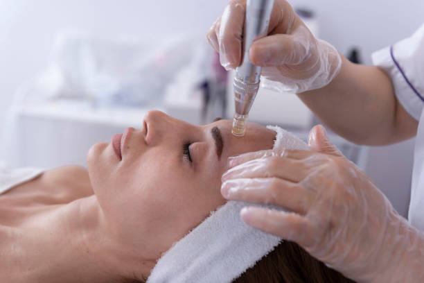 Professional administering facial treatment with syringe to a relaxed woman in a spa setting.